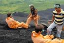As guide Anthony Alcalde (black T-shirt) and an aide offer instructions, two adventurers prepare to descend Cerro Negro on primitive toboggans.