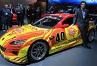 Patrick Dempsey stands next to a Mazda race car